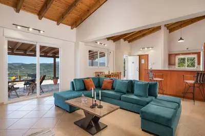 a living room with a blue couch and a table at Villa Cleronomia, private pool, seaview, in Kaloudhianá