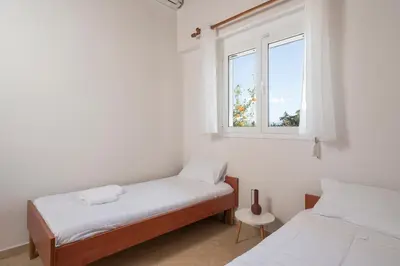 a white room with two beds and a window at Villa Cleronomia, private pool, seaview, in Kaloudhianá