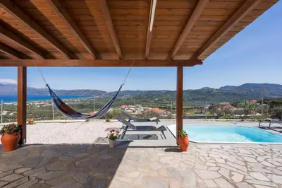 a patio with a hammock and a swimming pool at Villa Cleronomia, private pool, seaview, in Kaloudhianá
