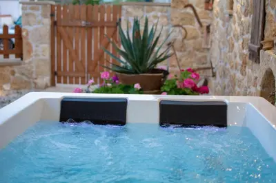 a bathtub filled with blue water in a yard at Pamelas House with Jacuzzi in Kissamos