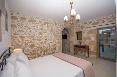 a bedroom with a bed and a stone wall at Pamelas House with Jacuzzi in Kissamos