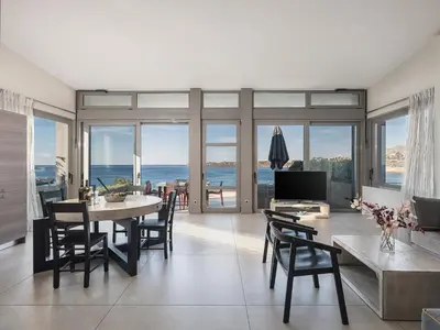 a living room with a table and chairs and the ocean at VILLA NIBA in Kalathas