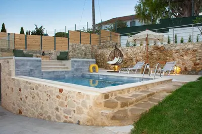 a pool with a stone wall and chairs in a yard at Casa Piedra in Nohia