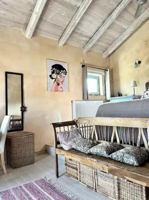 a bedroom with a bed and a bench in a room at Maison Théia, entre mer et montagne Samonas in Samonás