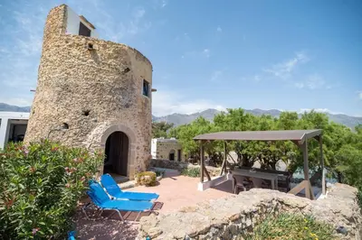 a stone building with blue lounge chairs and a fireplace at Mylos Seaside Experience in Frangokastello