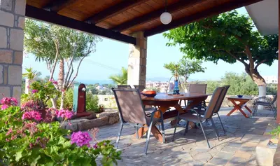 a wooden table and chairs on a patio with flowers at Anestis Ioanna Villa in Daratso
