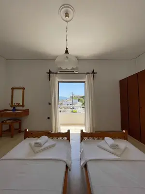 two beds in a room with a window at Aeolos Apartments Kolymbari in Kolymvari