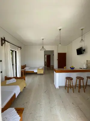 a bedroom with two beds and a kitchen with a counter at Aeolos Apartments Kolymbari in Kolymvari