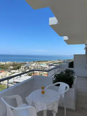 a white table and chairs on a balcony with a view at Aeolos Apartments Kolymbari in Kolymvari