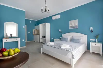 a blue bedroom with a white bed and a table at Evi Boutique Rooms in Galatás