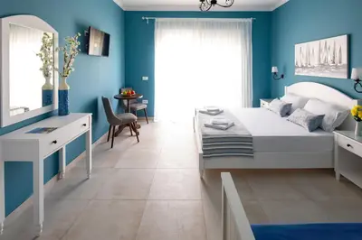 a bedroom with blue walls and a white bed and a mirror at Evi Boutique Rooms in Galatás