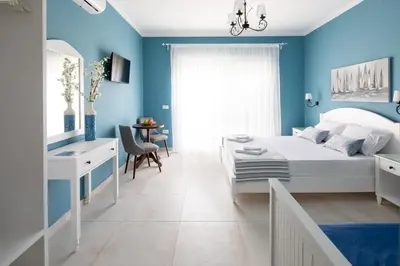 a bedroom with blue walls and a bed and a desk at Evi Boutique Rooms in Galatás