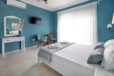 a bedroom with blue walls and a bed with a mirror at Evi Boutique Rooms in Galatás