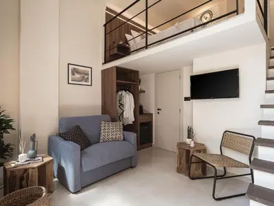 a living room with a blue chair and a tv at Copal Experience The Port in Chania Town