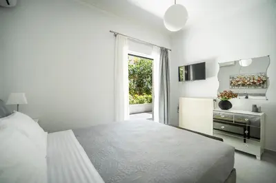 a white bedroom with a bed and a window at The Nest of Urban Living by 8essentially in Chania Town