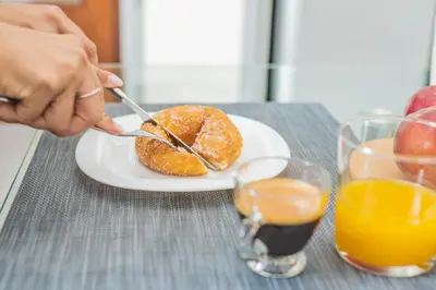 a person eating a donut on a plate with orange juice at The Nest of Urban Living by 8essentially in Chania Town