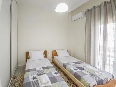 two twin beds in a room with a window at Fully renovated apartment close to the bus station and the city center! in Chania Town