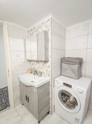 a small bathroom with a washing machine and a sink at Fully renovated apartment close to the bus station and the city center! in Chania Town