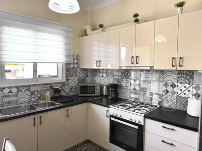 a kitchen with white cabinets and a stove top oven at Fully renovated apartment close to the bus station and the city center! in Chania Town