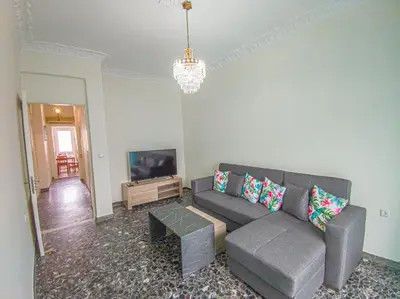 a living room with a gray couch and a tv at Fully renovated apartment close to the bus station and the city center! in Chania Town