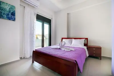 a bedroom with a bed with a purple blanket and a window at Fotini 's apartment near the city center. in Chania Town
