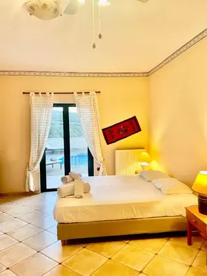 a bedroom with a bed and a large window at Olive Villa Plataniás in Xirokámbion