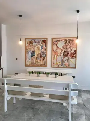 two white benches in a room with paintings on the wall at Aggelos and Thisbe Chania City Apartment in Chania Town