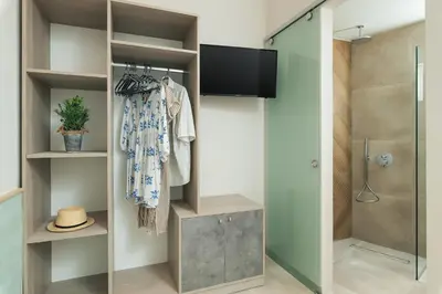 a bathroom with a walk in shower and a television at Stefanie Studios in Agia Marina Nea Kydonias