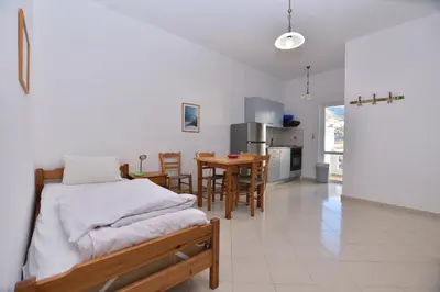a bedroom with a bed and a kitchen with a table at PALEOCHORA FINIKAS Apartments in Palaiochóra