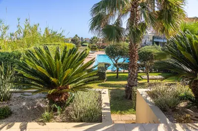 a garden with palm trees and a swimming pool at Maleme Yoga Blue in Chania Town