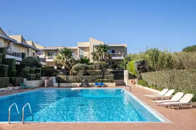 a swimming pool with lounge chairs next to a building at Maleme Yoga Blue in Chania Town