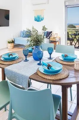 a dining room table with blue plates and chairs at Maleme Yoga Blue in Chania Town
