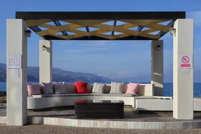 a couch under a pavilion with the ocean in the background at Beachfront villa Aqua Marine with private pool,ping-pong & BBQ in Chania Town