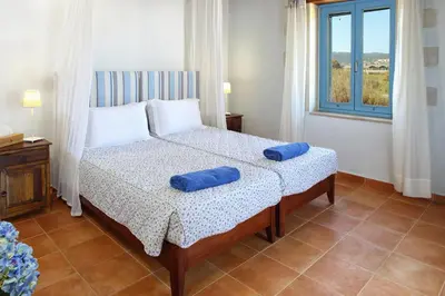 a bedroom with a bed with two blue pillows on it at Beachfront villa Aqua Marine with private pool,ping-pong & BBQ in Chania Town