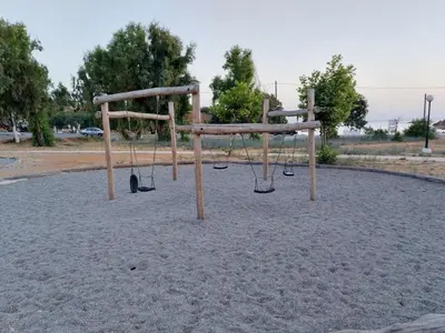 an empty playground with swings in a park at Chrissoula House In Agioi Apostoloi in Daratso