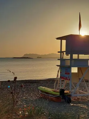 a lifeguard station on a beach with a surfboard at Chrissoula House In Agioi Apostoloi in Daratso