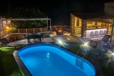 a backyard with a swimming pool at night at Casa Christina-Luxury Villa in Kissamos