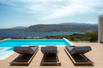 a swimming pool with two lounge chairs on a patio at Bay Overlook Villa in Korakiaí