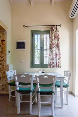 a white table and chairs in a room with a window at Casa Athelia: Traditional Home, Local Neighborhood in Chania Town
