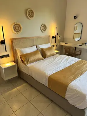 a bedroom with a large bed with white sheets and gold pillows at Electra Studios in Palaiochóra