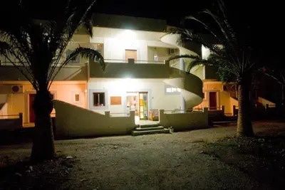 a house lit up at night with two palm trees at Electra Studios in Palaiochóra