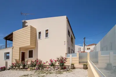 a white house with flowers in front of it at Luxury Katsoulakis Apartments in countryside in Alikianós