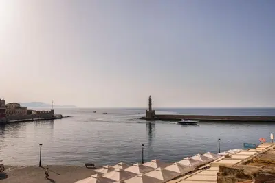 a beach with umbrellas and a lighthouse in the water at La vista de Pablo in Chania Town