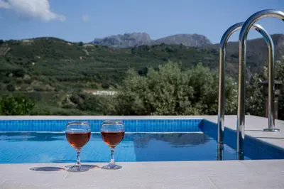 two glasses of wine sitting on a table near a swimming pool at Villa Margarita's farm, private pool in Maláthiros