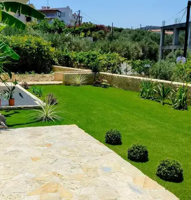 a garden with a green lawn with plants at Xenia's countryside guesthouse in Agia Marina Nea Kydonias