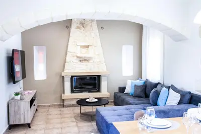 a living room with a blue couch and a fireplace at Sonio Villas - Que Bella Collection in Plataniás