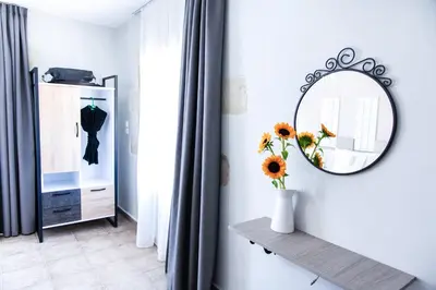 a room with a mirror and a vase with flowers on a shelf at Sonio Villas - Que Bella Collection in Plataniás