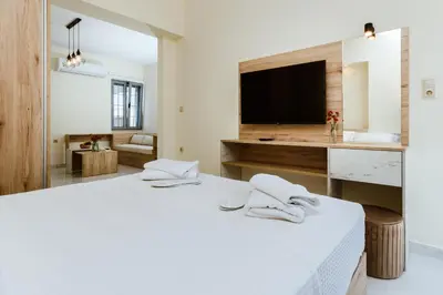 a white bedroom with a large bed and a tv at Emeli Suites in Chania Town
