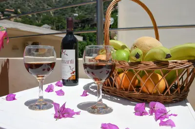 two glasses of wine and a basket of fruit on a table at Katerina's house in Kefálion