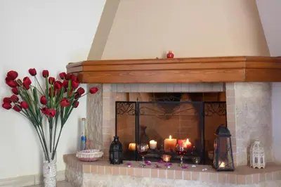a fireplace with candles and flowers and a vase of tulips at Katerina's house in Kefálion